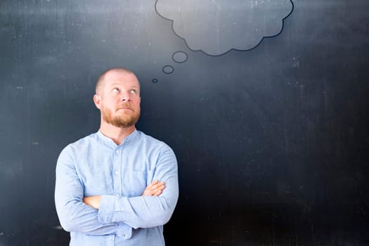 Hand drawn speech bubble on blackbord, casual business man looking at it. Creative idea and innovation concept...