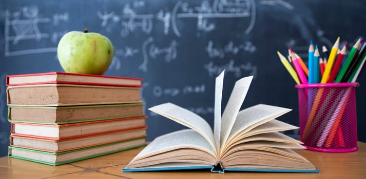 Back to School Concept. Accessories and books against chalkboard.