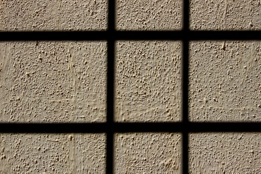 View of grain structure of wall lit by sunlight behind shaded bars