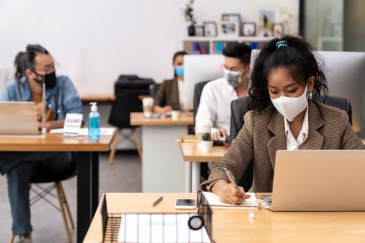 Mixed race of African black and asian business woman wear face mask working in new normal office with social distance to Group of business team people to prevent coronavirus COVID-19 spreading