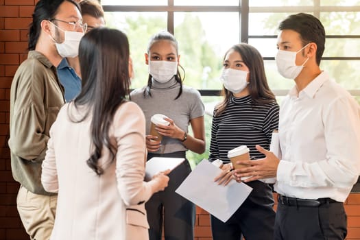 Group of business worker team meeting and brainstorm for startup new business. They wear protective face mask in new normal office preventing coronavirus COVID-19 spreading.