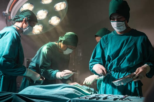 Operating room nurse prepare surgical equipment for surgeon doctor with Medical Team Performing Surgical Operation in Operating Room OR. Medical health care Surgery concept.