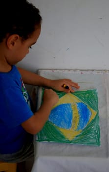 salvador, bahia / brazil - september 3, 2020: child paints pabeira do Brasil with crayons at his home in the city of Salvador.