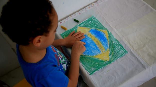 salvador, bahia / brazil - september 3, 2020: child paints pabeira do Brasil with crayons at his home in the city of Salvador.