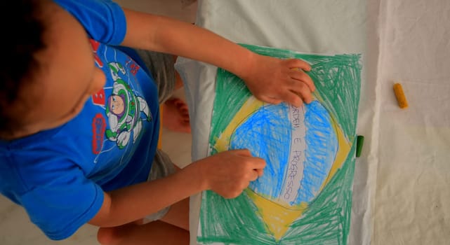salvador, bahia / brazil - september 3, 2020: child paints pabeira do Brasil with crayons at his home in the city of Salvador.