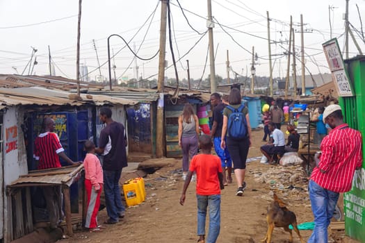 Nairobi, Kenya - July 10, 2017: Tourists and locals walking at street of Kibera slum in Nairobi, Kenya.