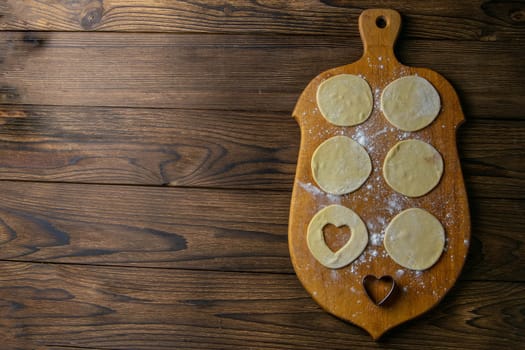 Heart shaped dumplings, flour on wooden background. Cooking dumpling. Top view with clear space.