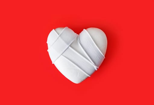 White heart with white bracelets on red background.