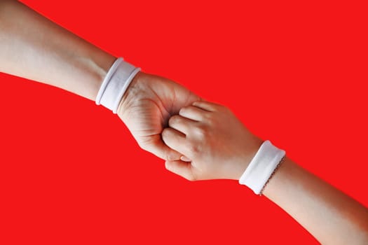 Helping hand to a friend. Female hands with white bracelets on red backgroung.