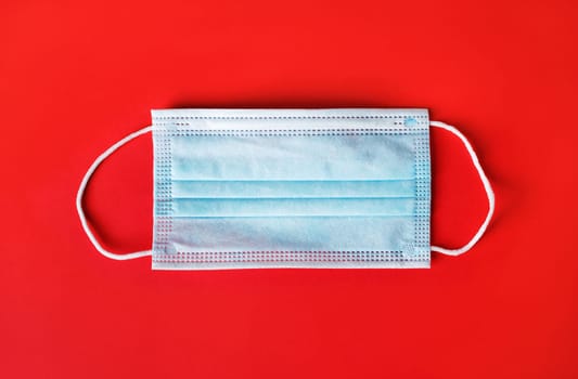 Protection face mask against coronavirus over red background.