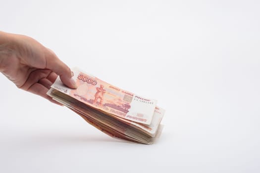 Hand holds out a bundle of five thousandth Russian banknotes