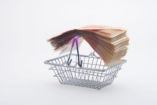 On the handles of the grocery basket is a large stack of paper bills, viewed from the side