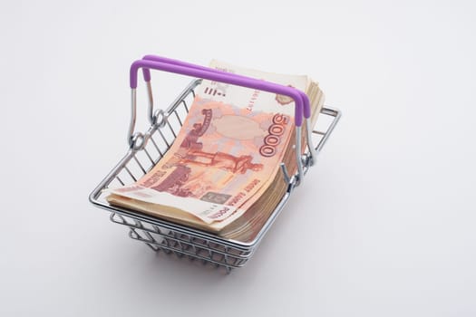 A large bundle of Russian bills is in a grocery basket, white background
