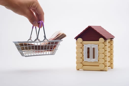 A hand brings a basket with a wad of money to the house
