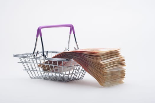 There is a large stack of bills on a grocery basket, viewed from the side