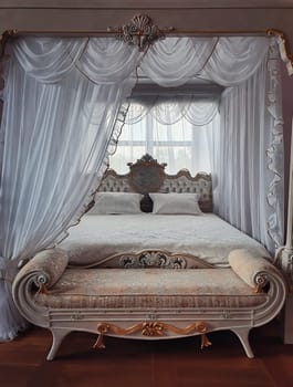 Ancient bedroom furniture style, medieval king bed, near the window, white curtains canopy and gold details. Close up background of a beautiful room luxuriously decorated for prince or princess.