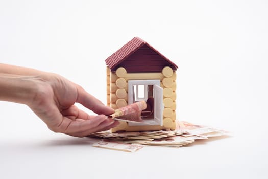 Hand puts a bill into the door of the toy house
