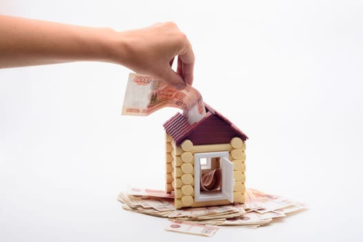 Hand shoves a five thousandth bill into the roof of a house
