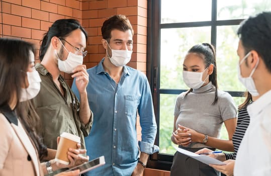 Group of business worker team meeting and brainstorm for startup new business. They wear protective face mask in new normal office preventing coronavirus COVID-19 spreading.