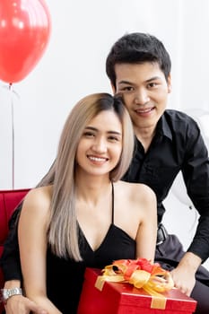Portrait of couple holding gift box present celebrating New Year Party festival holiday in living room