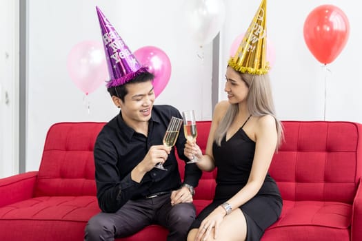 Young asian adult couple celebrating New year christmas holiday with sparkling wine together in living room of big condominium in big city