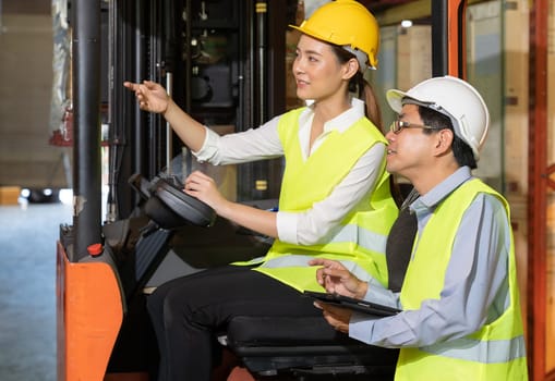 Female young asian warehouse forklift workers discuss about inventory to male warehouse manager in large distrubution warehouse background. Reopening business warehouse inventory and logistic concept