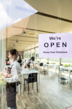 Reopening restaurant signage with social distance for new normal restaurant with background of asian waiter and waitress prepare restaurant before open. New normal restaurant lifestyle concept.