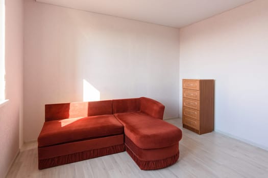 The interior of a room that was empty before the move, there is a sofa and a chest of drawers in the room