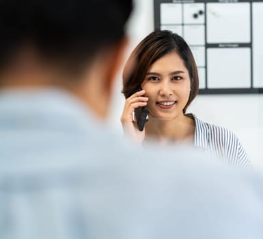 Businesswoman working and making a call in home office with social distance using screen partition to prevent from coronavirus COVID-19 spreading. New normal concept after pandemic.