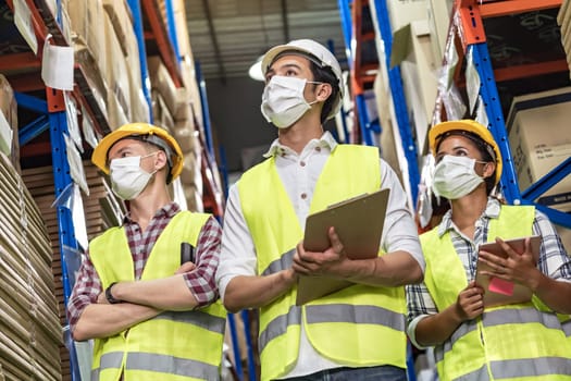 Portrait of Interracial group Asian African and Caucasian with clipboard and barcode scanner wear face mask to prevent COVID-19 coronavirus infection in distribution center. Business teamwork concept.