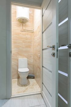 Open door to a small toilet, a water heater is located upstairs