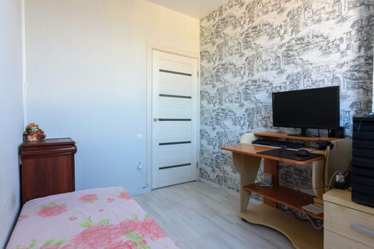 Anapa, Russia - June 22, 2020: Bedroom interior with poor furniture and computer desk