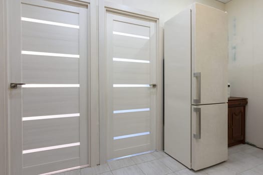 Two interior doors in the apartment, there is a refrigerator on the right