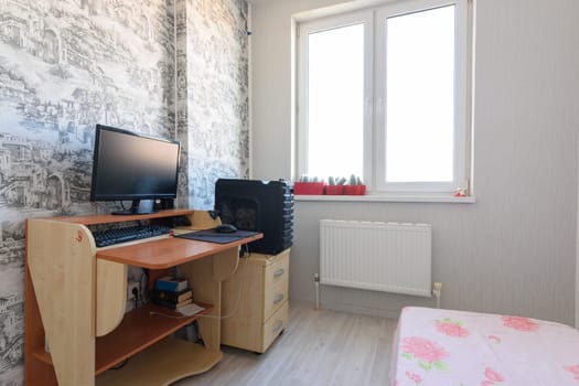 Anapa, Russia - June 22, 2020: Poor living room interior with sparse furniture and computer table