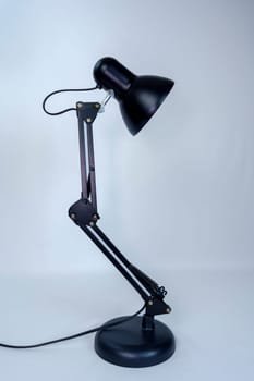 Black metal desk lamp with an adjustable articulated arm and round base, isolated on a white background. Modern and functional lighting for workspace or study areas