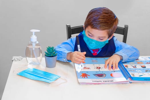 Calgary, Alberta, Canada. Sep 6, 2020. A kinder garden, pre-school student learning with an activity work book with a face mask and hand sanitizer on a desk. Concept: Back to school during coronavirus, covid-19, pandemic, new normal.