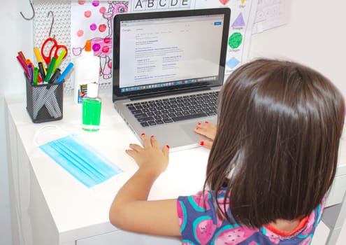 Calgary, Alberta, Canada. Sep 5, 2020. A elementary school student looking at a computer monitor with a face mask and hand sanitizer on a desk.