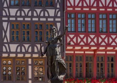 Statue Statue lady justice in front of the half-timbered houses on the Roemerberg in Frankfurt, Germany the judge in front of the half-timbered houses on the Roemerberg in Frankfurt, Germany