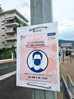 Menton, France - August 29, 2020: Coronavirus COVID-19 Face Mask Is Mandatory In The City Center Of Menton Says This Street Sign, France, Europe