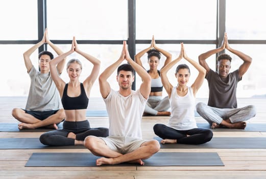 Healthy Lifestyle Concept. Young sporty people practicing yoga in group, sitting in tree pose in studio and smiling at camera