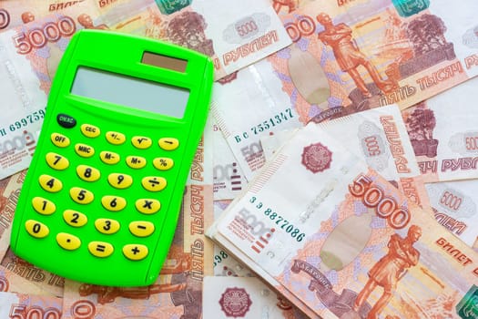 Green calculator and a bunch of five thousandth bills