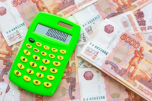 Against the background of money is a bundle of five-thousandth bills and a calculator with the number one million