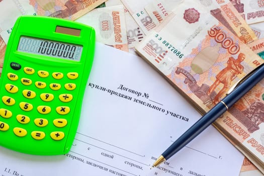 The contract for the sale of the land plot contains a calculator, a wad of money and a pen