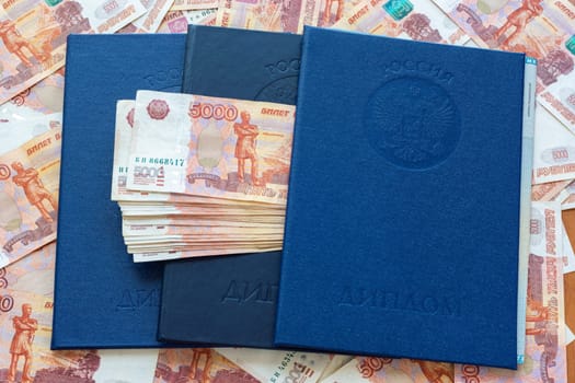 Three blue higher education diplomas lie in the background from the money, a bundle of money sticks out between the diplomas