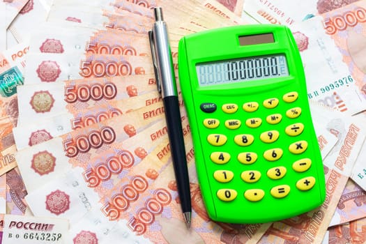A calculator with the number one million and a ballpoint pen lie against the background of Russian five-thousandth bills