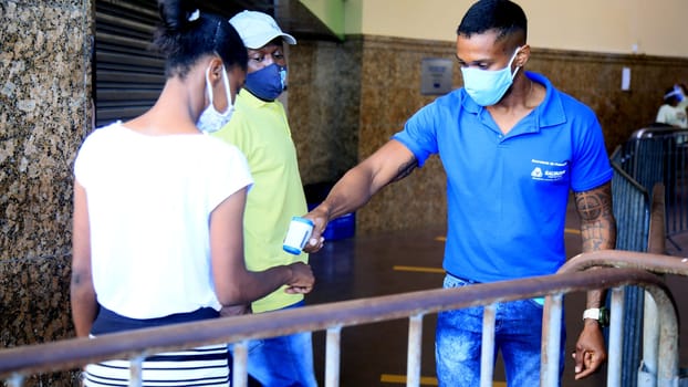 salvador, bahia / brazil - september 9, 2020: person uses thermometer to measure pedestrian temperature to access the Lacerda elevator in the city of Salvador.
