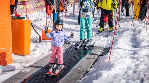 Young, happy skier girl going up on conveyor lift belt to green ski zone for ski lessons, Bialka Tatrzanska, Tatry, Poland