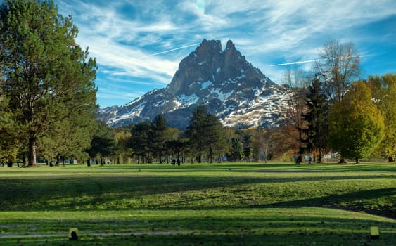 a green golf field and Pic du Midi Ossau