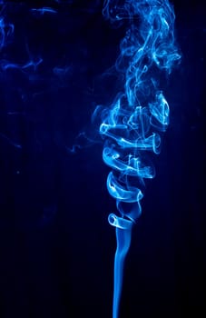 Blue abstract shaped smoke against black background. Abstract background. Selective focus