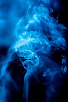 Blue abstract shaped smoke against black background. Abstract background. Selective focus